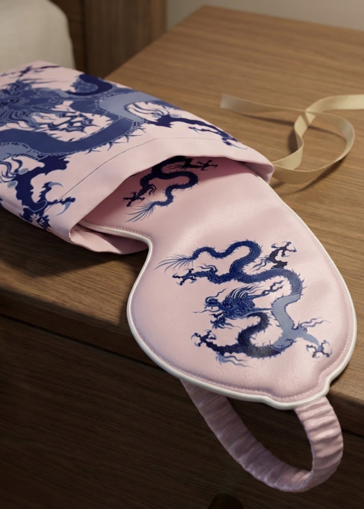 Pink silk eye mask with blue dragon design and matching cloth gift bag.