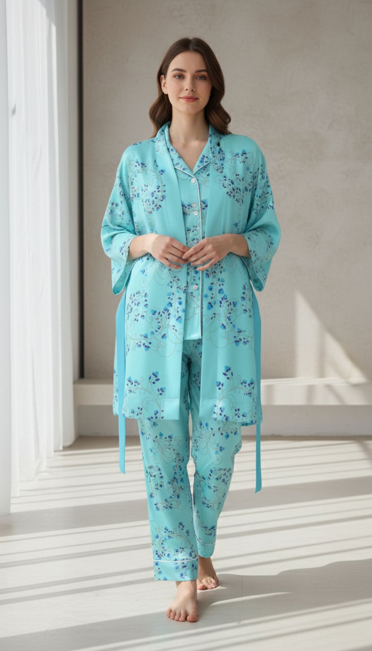 Woman wearing a turquoise floral pajama set standing in a room with white walls and a window.
