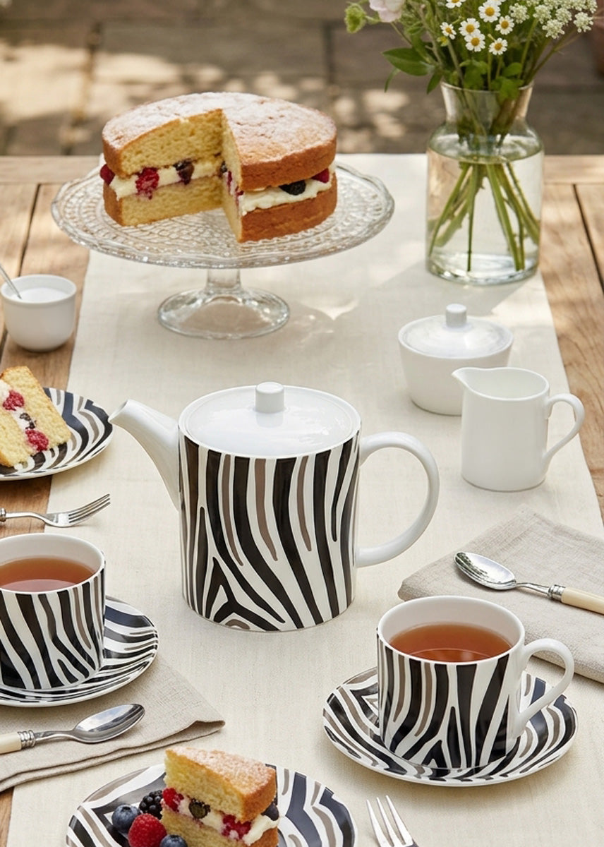 Zebra stripe pattern o a bone china teapot and matching cups and saucers on a table set for tea.