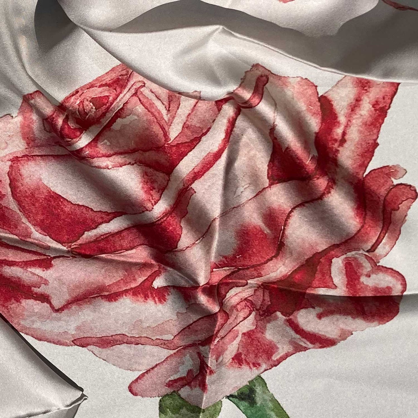 Detail of a square cream-colored scarf with a pink and red rose design.