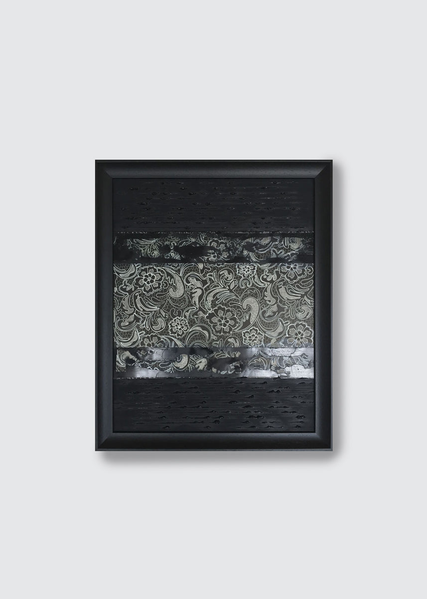 A framed abstract art painting featuring textured black sections and a central horizontal band with gray and white paisley lace patterns, displayed against a light gray wall.