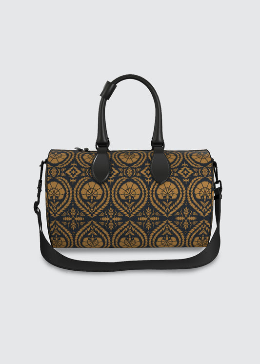 A structured duffel bag with a dark navy blue and ochre damask pattern, featuring black leather handles and a matching black shoulder strap, set against a solid light gray background.