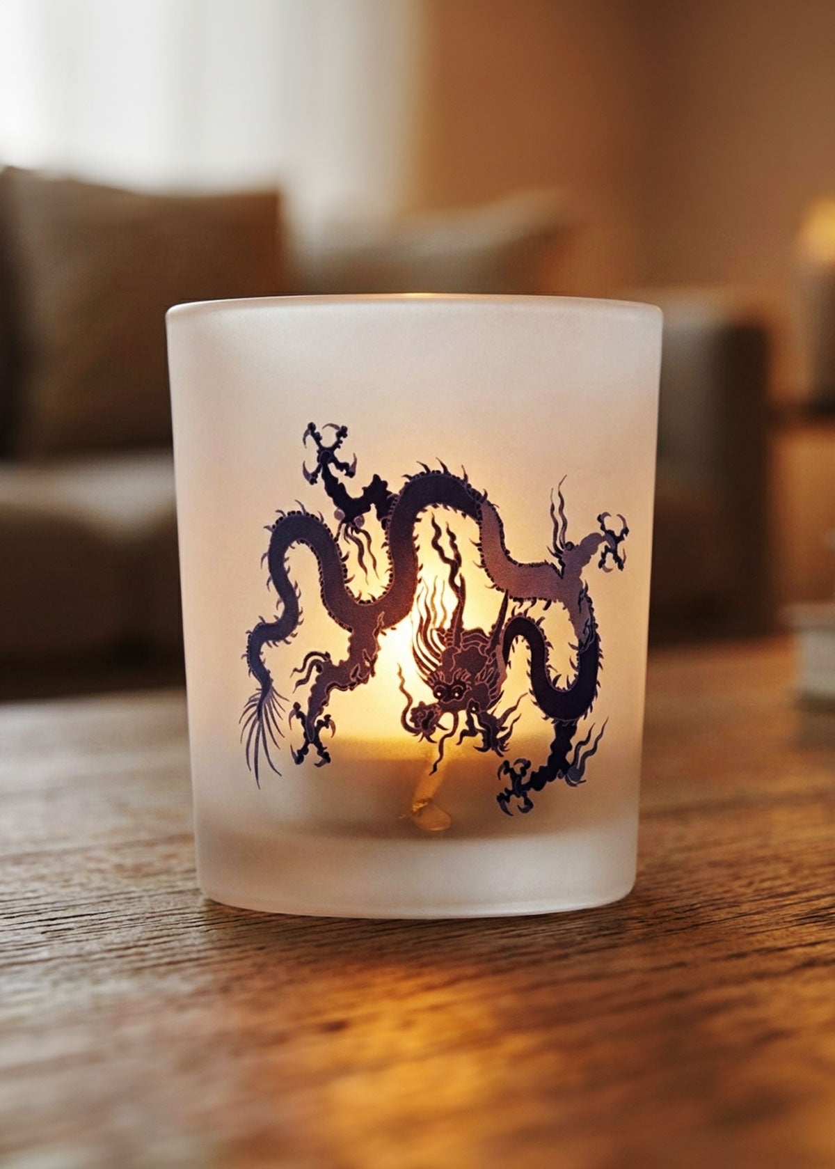 Frosted glass tealight candle holder with blue dragon design on a wooden surface.