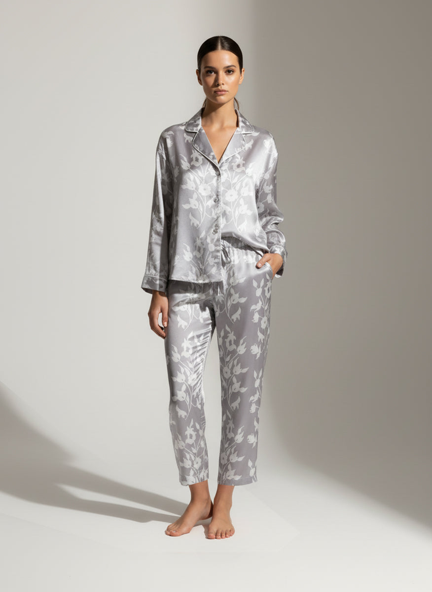 Woman wearing a white floral on grey pajama set on a plain background