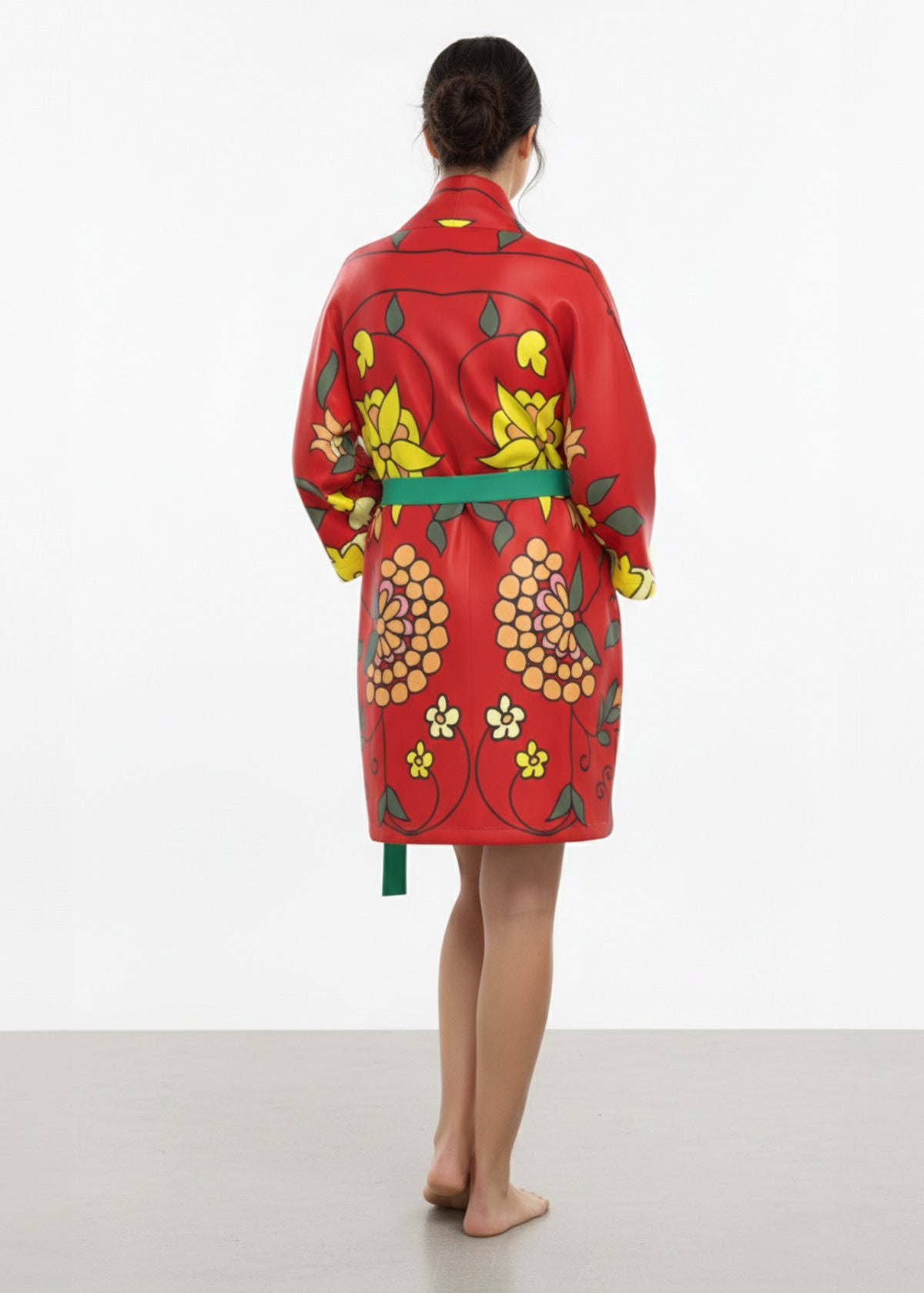 Person wearing a red floral-patterned silk kimono robe showing the rear view on a white background