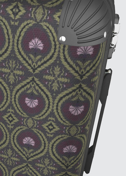 Close-up of a patterned suitcase surface with a repeating ornamental acanthus medallion and wreath design in olive green, burgundy, and lavender, alongside a dark gray moulded plastic corner component.