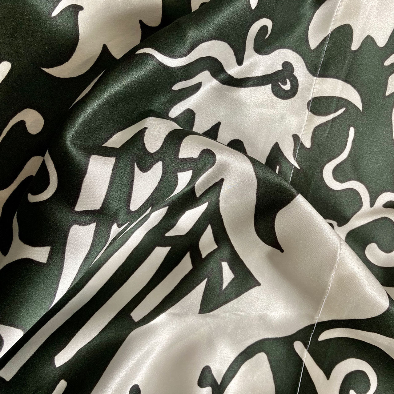 A detail of the design on a silk kimono of a white phoenix pattern on a green background.